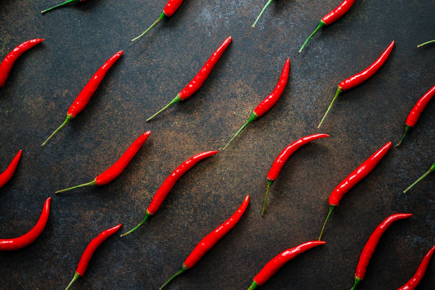 a-lot-of-chili-peppers-on-a-kitchen-table-top-view-MC2X8WH.jpg